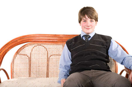 Young teenager sitting on wicker chair and looking at camera. Isolated over white backgroundの写真素材