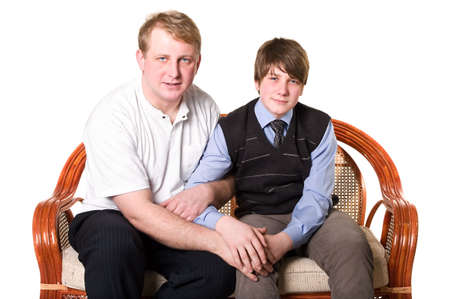 Father and son a teenage are sitting on sofa and holding hands. Isolated on white background. Studio shotの写真素材