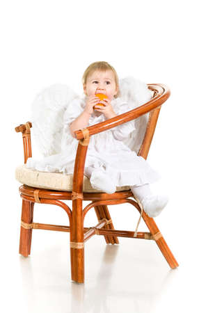 Child sitting on the chair with orange fruit. Studio shot. In angel`s wingsの写真素材