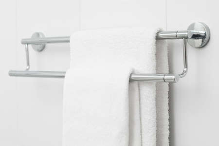 Two white bath towels hanging on white tile wallの写真素材