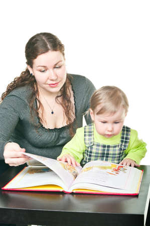 Little child and mother together read the book at a table. It is isolated on a white backgroundの写真素材
