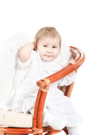 Child sitting on the chair. Studio shot. Isolated on white background. In angel`s wingsの写真素材