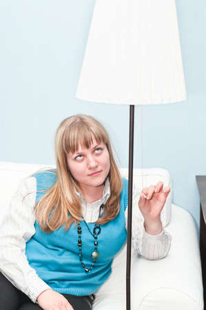 The girl the blonde includes the fixture sitting on a sofa in a roomの写真素材