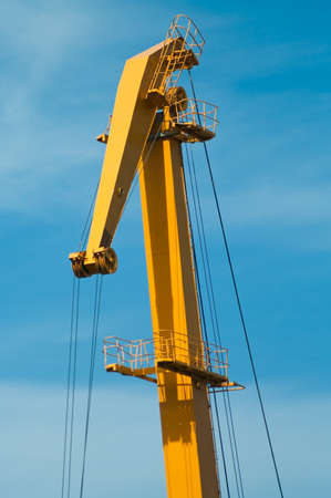 Yellow boom of harbour crane on blue skyの写真素材