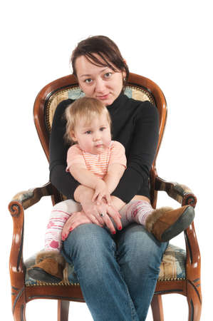 Young mother ans daughter are sitting on chair. Isolated over white backgroundの写真素材