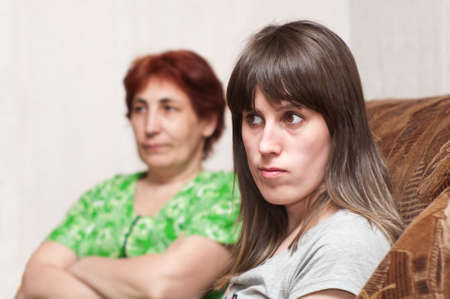 Mature woman a mother and young girl a daughter together on sofaの写真素材