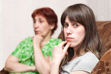 Mature woman a mother and young girl a daughter together on sofaの写真素材