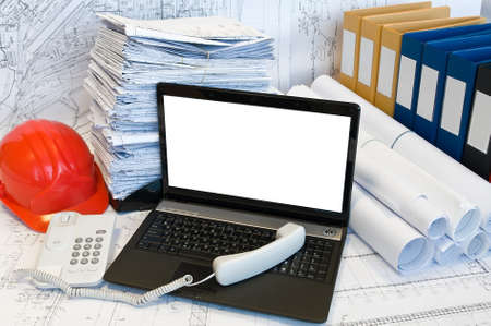 Opened laptop, phone handset and stack of project drawings. Rolled papers. Working place. White screenの写真素材