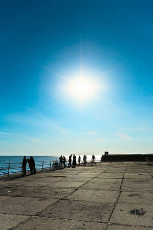 Bright sun on blue sky. Sea coast with peopleの写真素材