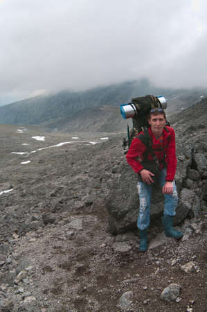 Backpacker a young man sitting on rock in mountainsの写真素材