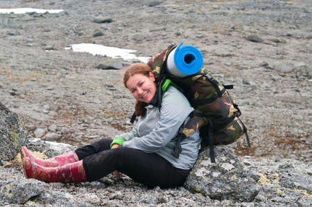 Backpacker a young woman sitting on rock in mountainsの写真素材