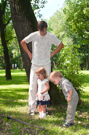 Father and little children in park in summer day playingの写真素材