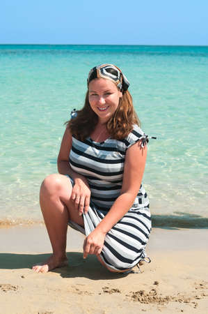 Young pretty girl on a sandy beach near the shore blue seaの写真素材