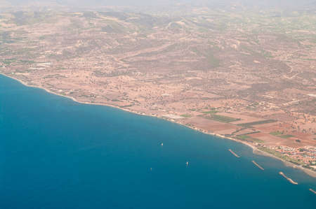 The view from an airplane in island of Cyprus. Seacoast line with blue Mediterranean sea and brown land.の写真素材