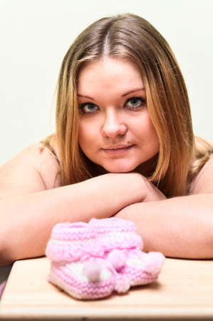 Pregnant young Caucasian woman looking at baby`s pink bootee.の写真素材