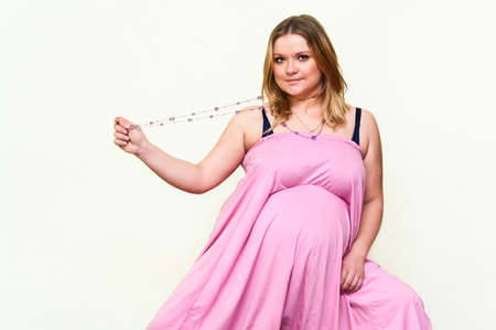 Pregnant young Caucasian woman in pink dressの写真素材