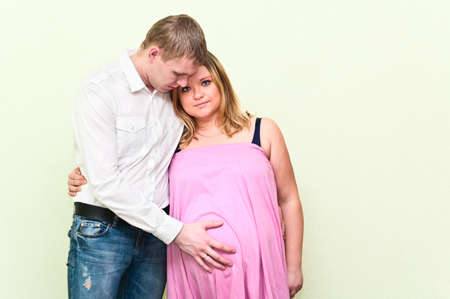 Pregnant woman with her husband standing near a wall. Caucasians, a loving young coupleの写真素材