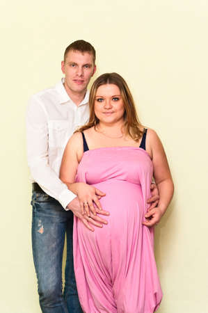 Pregnant woman with her husband standing near a wall. Caucasians, a loving young coupleの写真素材