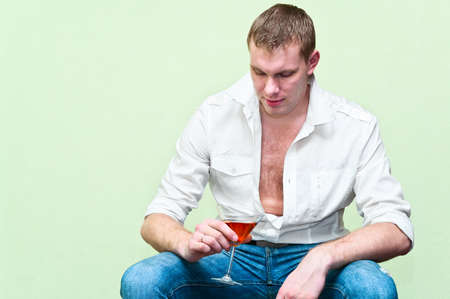 Handsome man sitting with glass of alcohol. Caucasian gayの写真素材