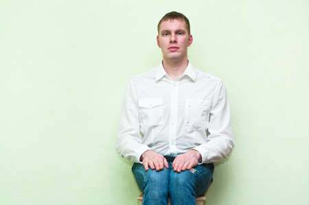 Handsome young man sitting near the wall. Copy spaceの写真素材