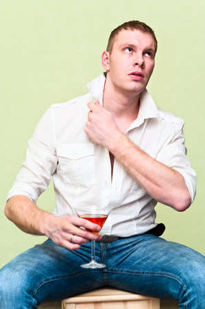 Handsome man sitting with glass of alcohol. Caucasian gayの写真素材