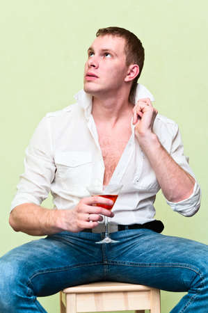 Handsome man sitting with glass of alcohol. Caucasian gayの写真素材