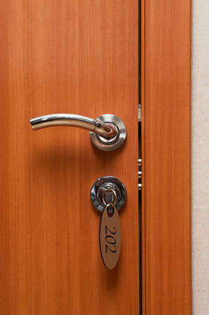 Door handles on wood wing of door and key in keyhole with numbered labelの写真素材