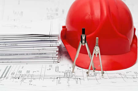 Orange hard hat, compasses and heap of project drawingsの写真素材