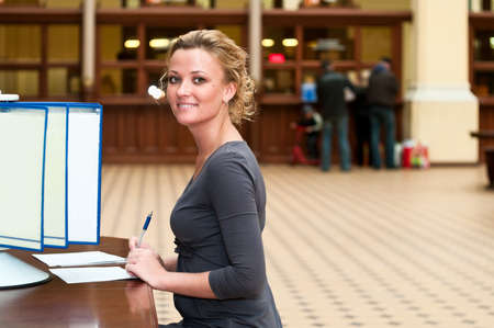 Young beautiful blond girl sitting at a table near the bar with the information and looks forの写真素材