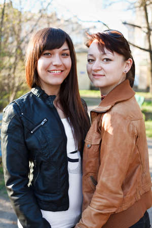 Portrait of two young beautiful women a girlfriend. Standing together. Looking at camera and smilingの写真素材