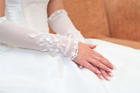Women's hands on a white wedding dress. Bride seating, unrecognizableの写真素材