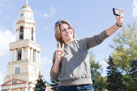 Young beautiful Russian woman photographing himself against the churchの写真素材