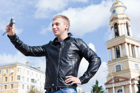 Young handsome man photographing himself, outdoorsの写真素材