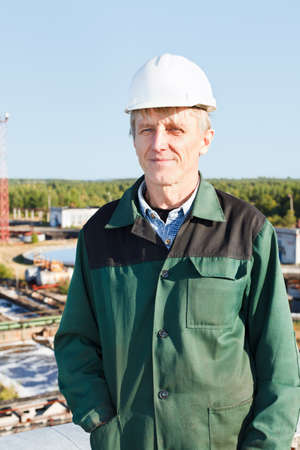 Mature man manual worker in white hardhat near sewage treatment basin