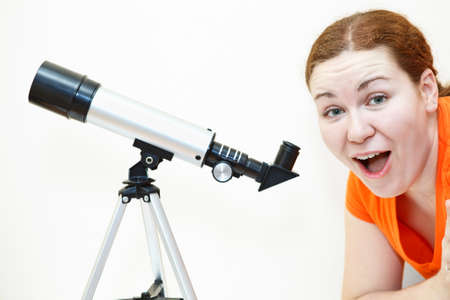 Surprised young woman in orange t-short with telescope on white backgroundの写真素材