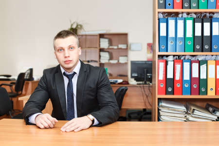 Handsome male business executive sitting behind a bookstandの写真素材