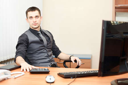 Young business man sitting at table and working on computerの写真素材