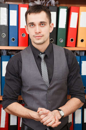 Handsome male business executive sitting behind a bookstand