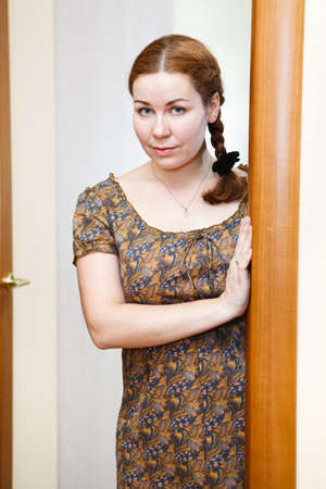 Portrait of young Caucasian female in dress standing in domestic roomの写真素材