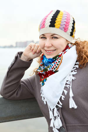 Portrait of happy young Caucasian female with red bag standing on embankment の写真素材
