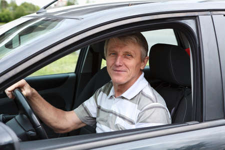 Happy senior person sitting in car on driver seat の写真素材