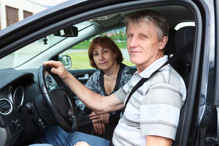 Senior Caucasian husband and wife sitting in land vehicle and smiling