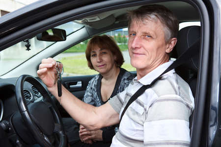 Senior Caucasian male and woman sitting in new car and holding ignition keyの写真素材