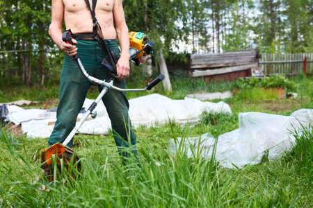 Unrecognizable lawn-mower with chopper trimer mowing grass  Focus on trimerの写真素材