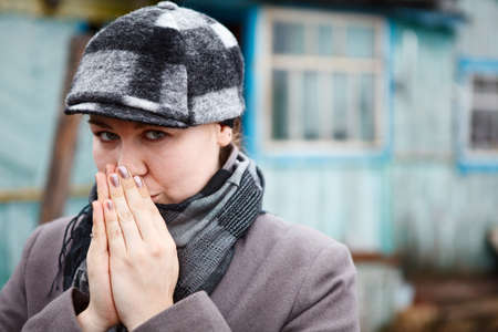 Woman close up portrait in cap and scarf with clasped hands  Copy spaceの写真素材