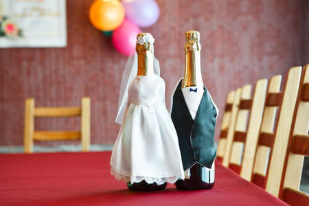 Two bottles of champagne in bride and groom clothes on table.の写真素材