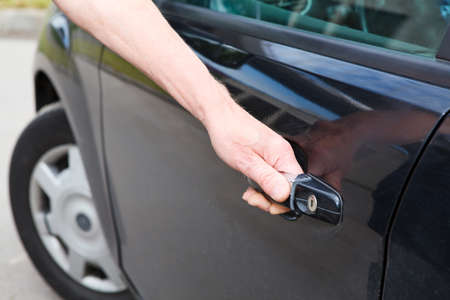 Male a driver opening car door of black land vehicle