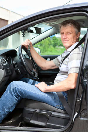 Happy mature man with car key sitting in own land vehicleの写真素材