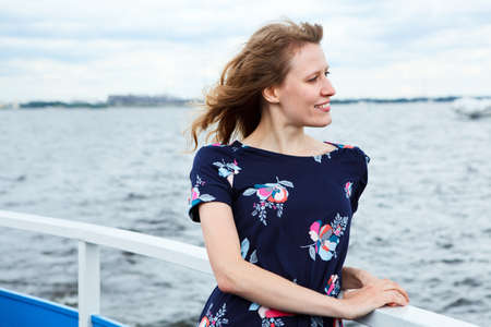 Girl standing on the deck of cruise yacht on wind and looking far awayの写真素材