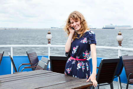 Standing woman on ship deck with mobile telephoneの写真素材